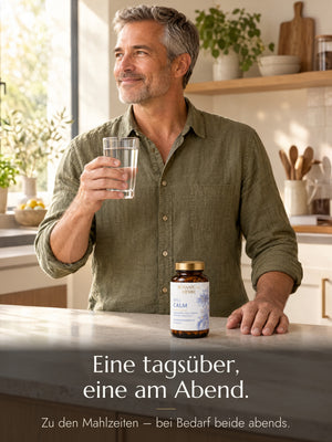 Ein Mann hält schmunzelnd ein Wasserglas, vor ihm auf der Arbeitsplatte ein Glas N°03 Calm. Bildtext: Eine tagsüber, eine am Abend. Zu den Mahlzeiten – bei Bedarf beide abends.