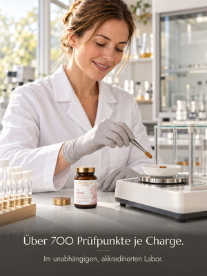 Eine Laborantin legt mit einer Pinzette eine Kapsel aus einem Glas N°01 Glow in eine Wägeschale. Bildtext: Über 700 Prüfpunkte je Charge. Im unabhängigen, akkreditierten Labor.